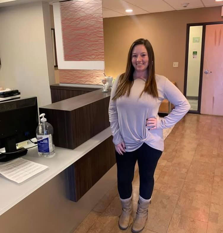Woman standing in front of reception desk with a smile on her face.