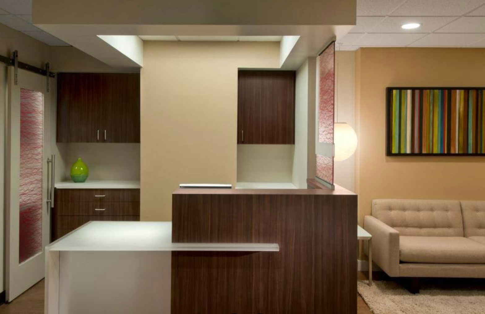 The image shows a modern kitchen interior with sleek cabinetry, an island countertop, a stainless steel sink, a wooden floor, and contemporary decorative elements.
