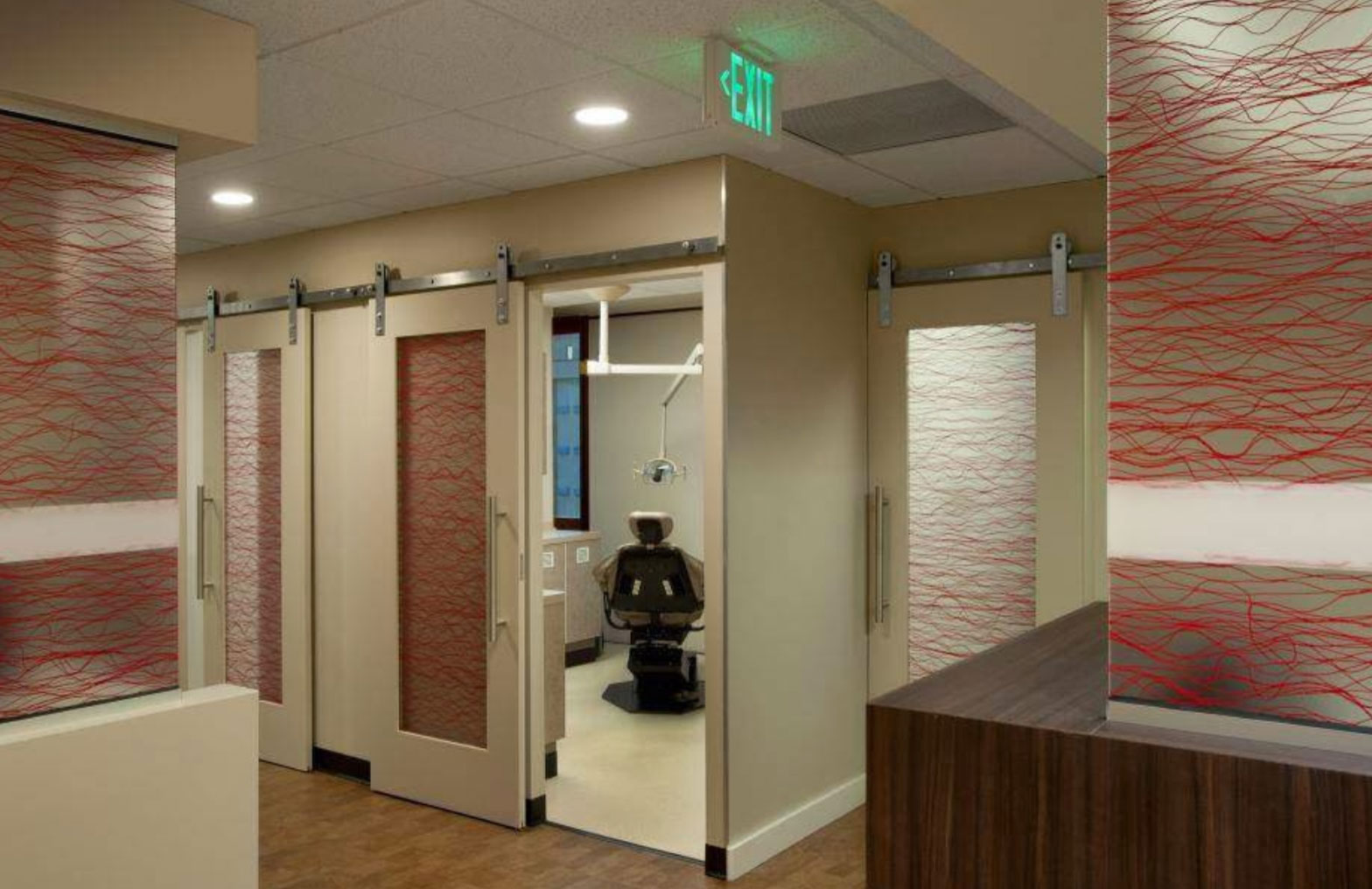 The image shows an interior space with a modern design, featuring a colorful abstract wall art, a red and white striped patterned door, and a contemporary style hallway with sliding doors and a sleek metal railing.